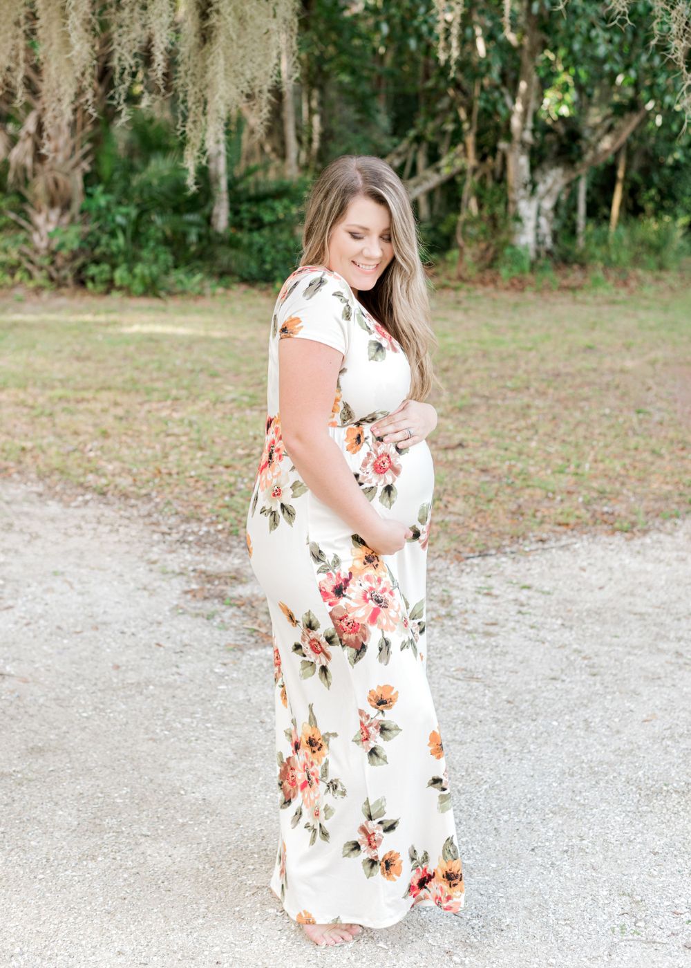 Maternity portrait in floral maxi dress against Spanish moss backdrop.