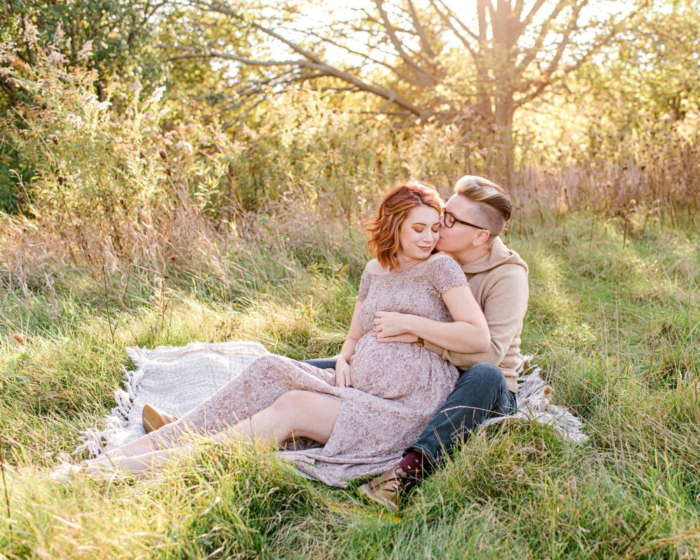 A couple relaxes on a blanket in a sunny meadow during golden hour.