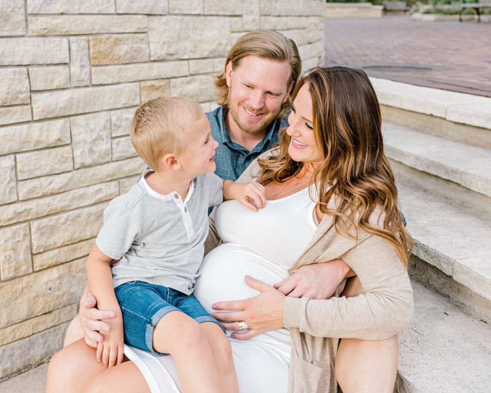 A family shares a tender moment together on stone steps outdoors.