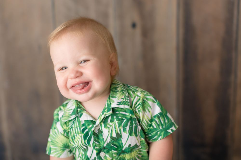 Close-up portrait with tropical print shirt against wooden backdrop.