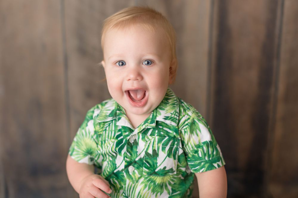 Enthusiastic expression captured in tropical print shirt against rustic background.