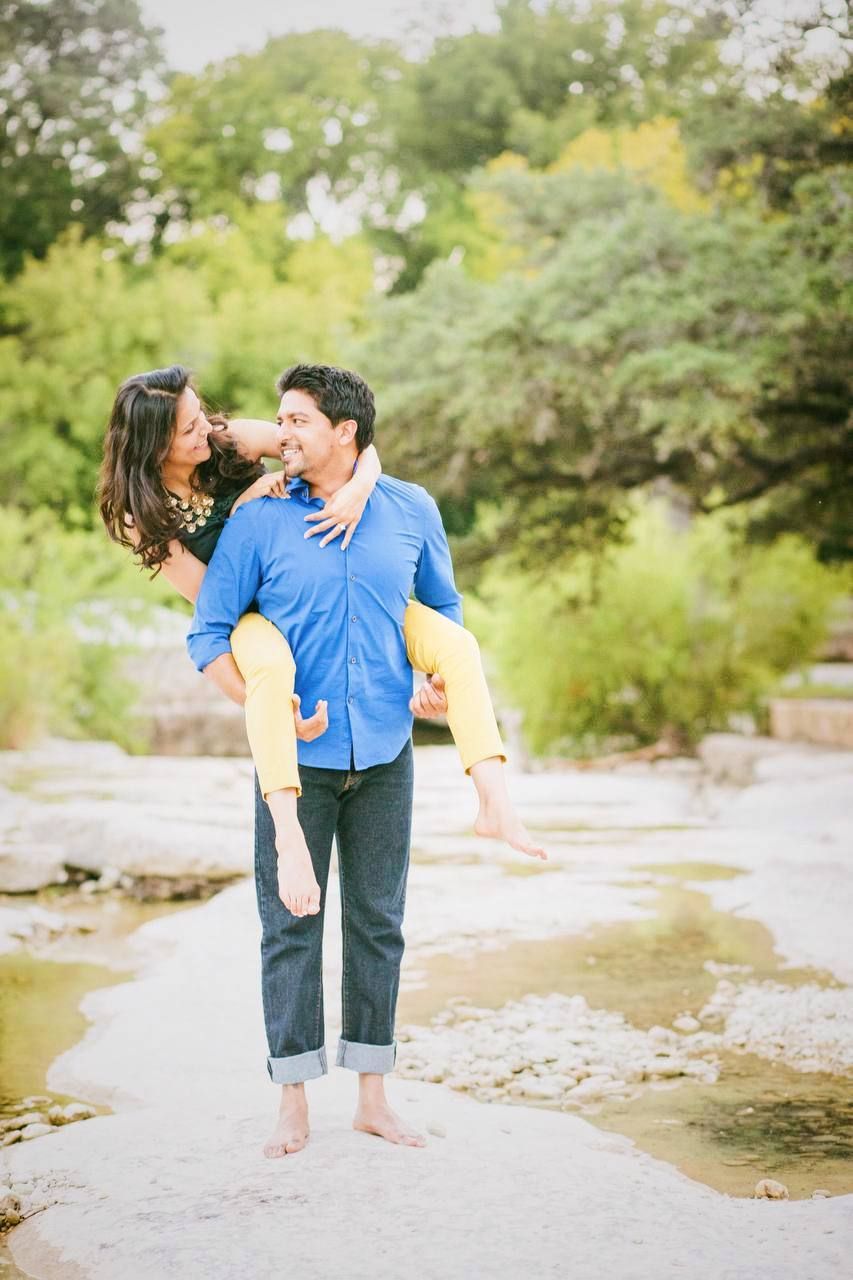 A playful moment captured between a couple standing on rocks near a creek.