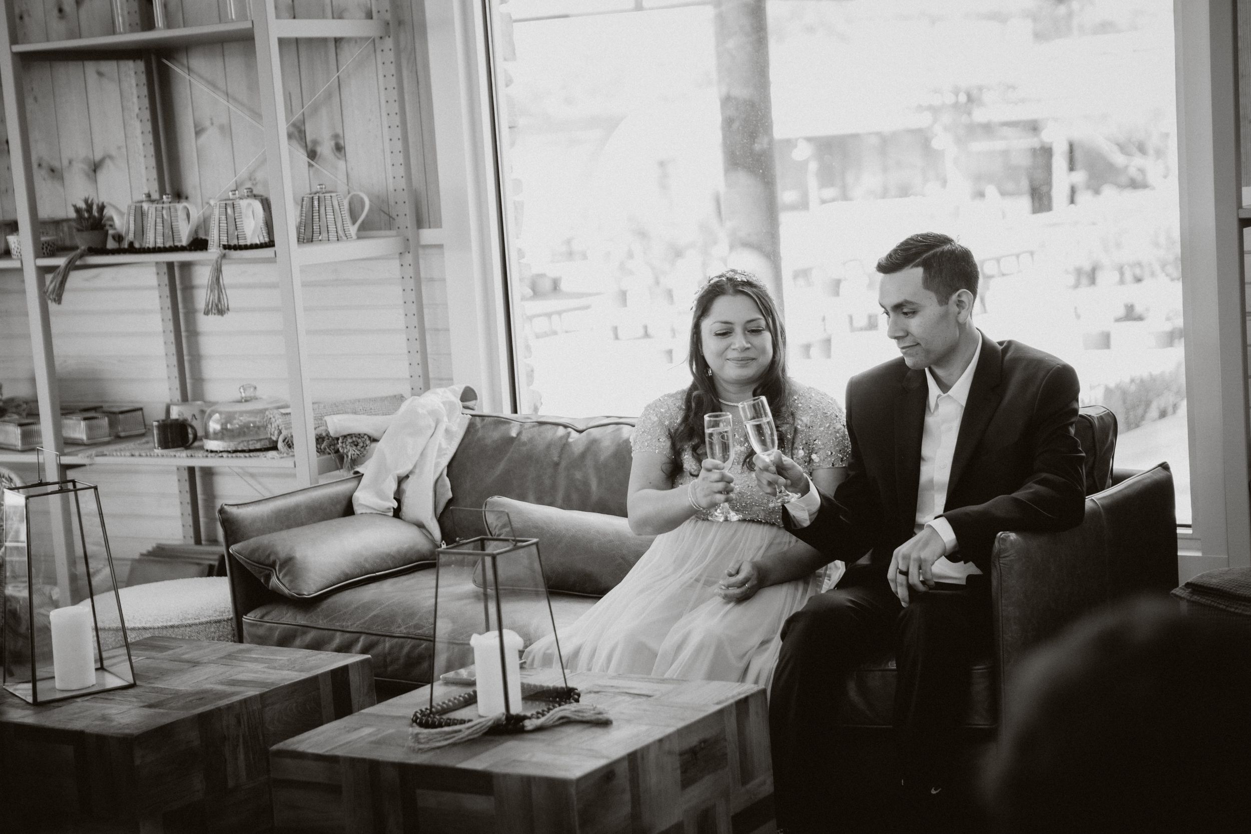 A relaxed couple enjoying drinks together on a modern sofa in a bright indoor setting.