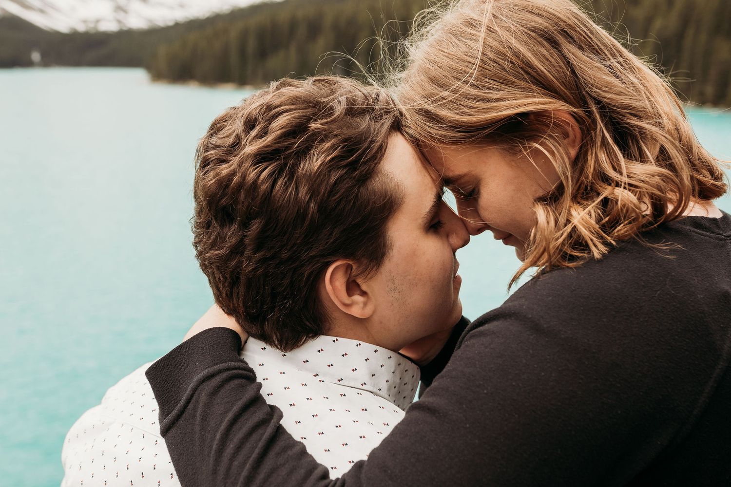 An intimate moment shared between a couple overlooking a pristine mountain lake.