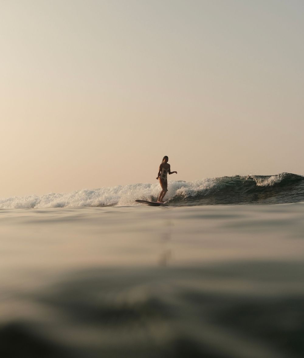 girl surfing a longboard during sunrise