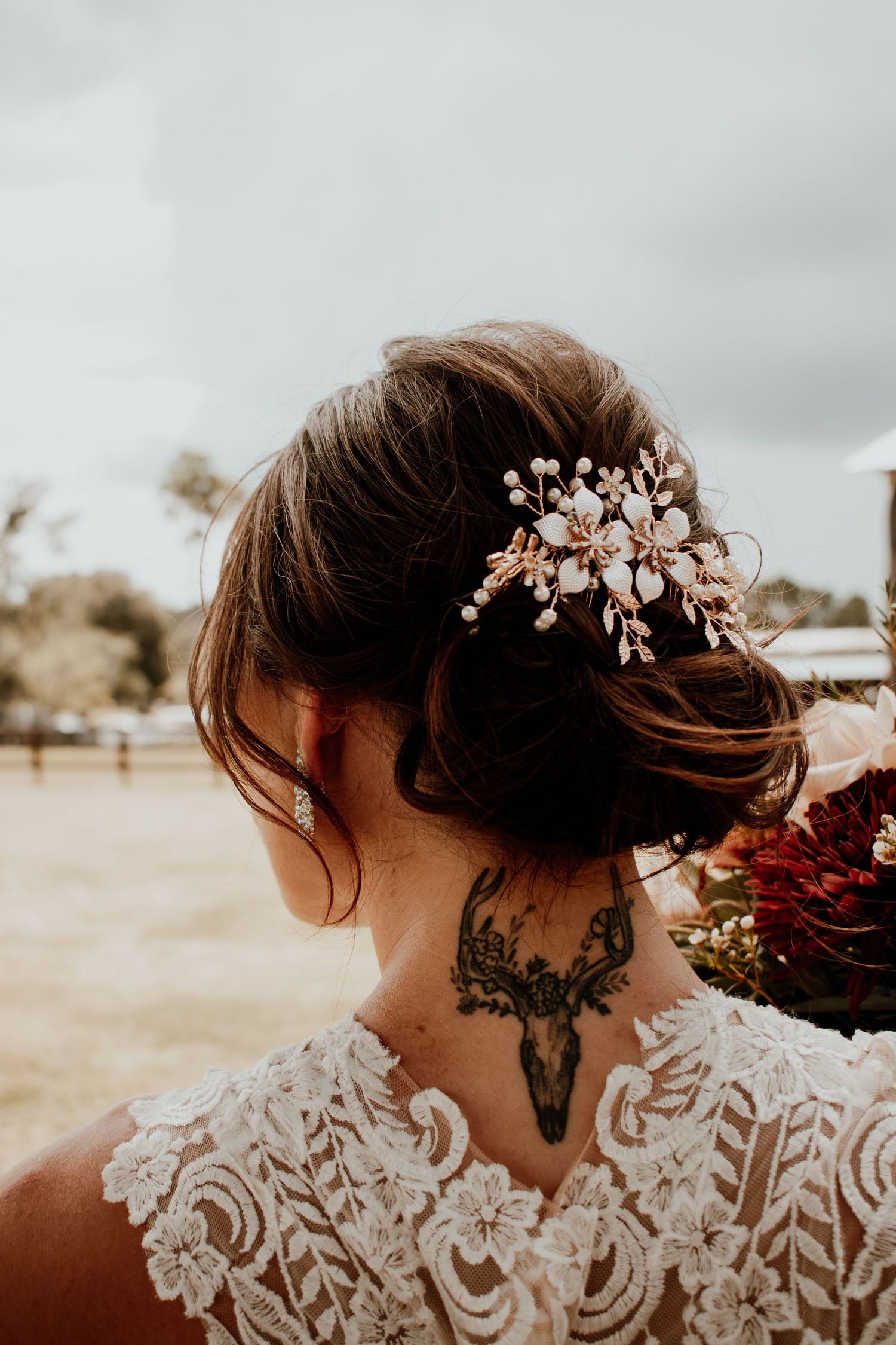 Detail shot of bridal hair accessories and lace dress against moody sky.