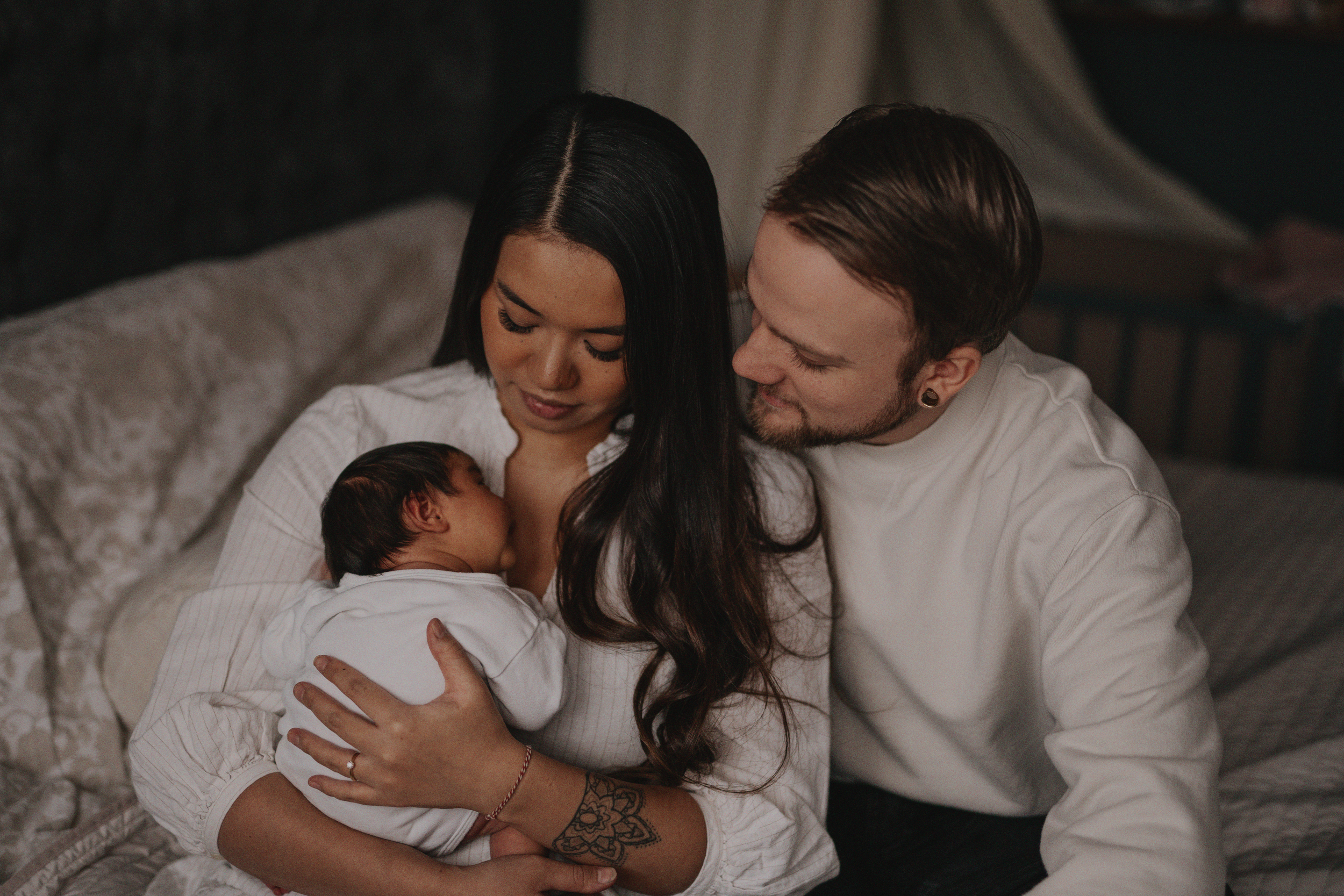 Intimate family portrait with newborn baby in cozy indoor setting.