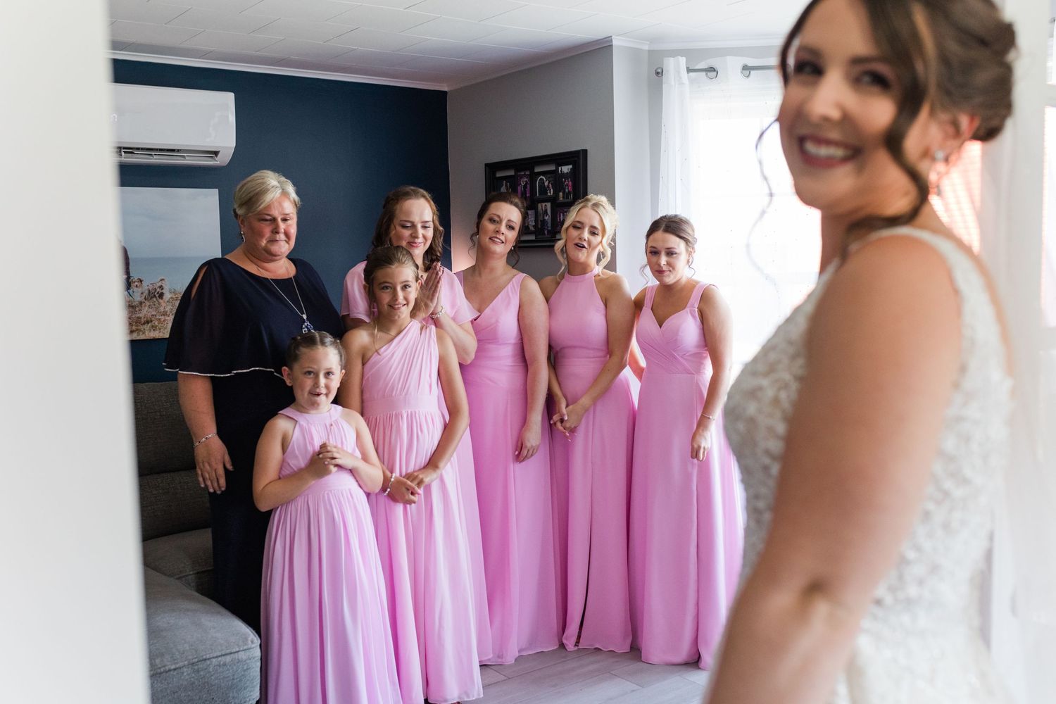 Wedding party members in matching pink gowns share a joyful pre-ceremony moment.