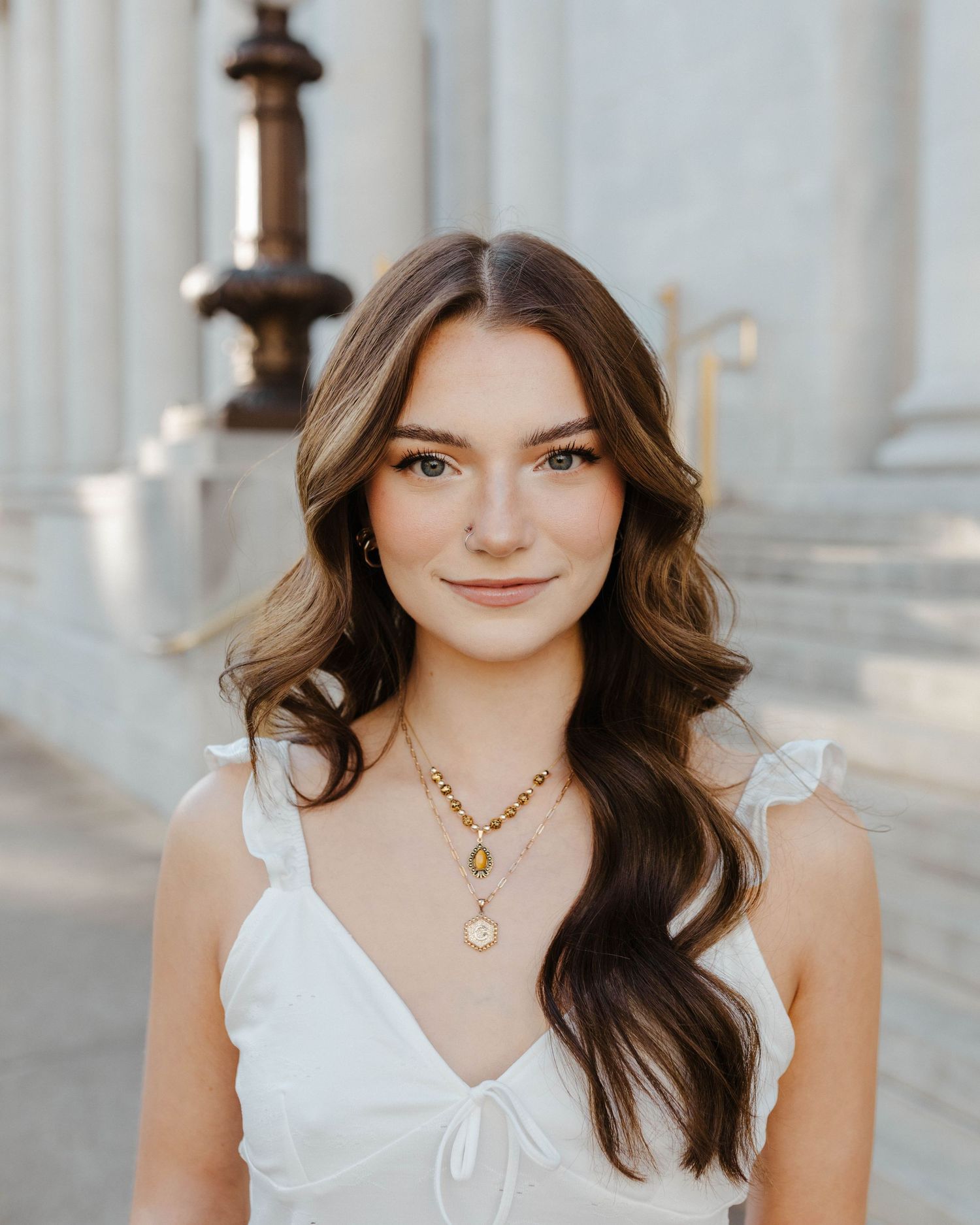 Portrait of woman in white dress with wavy hair against classical architecture.