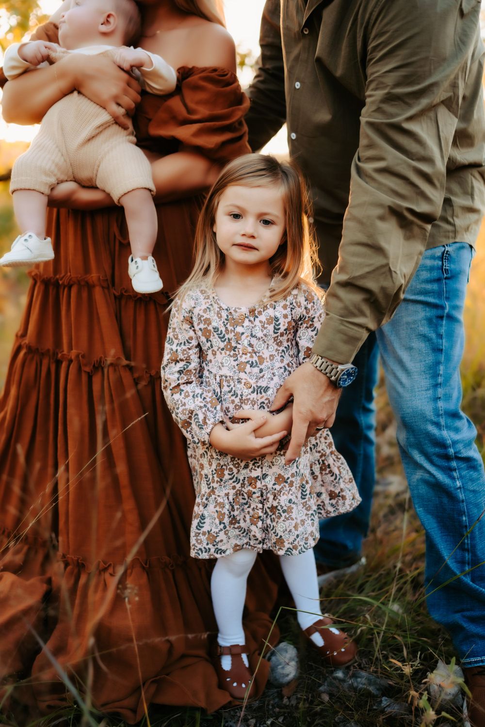 Family portrait with parents, young girl, and baby in autumn outdoor setting.