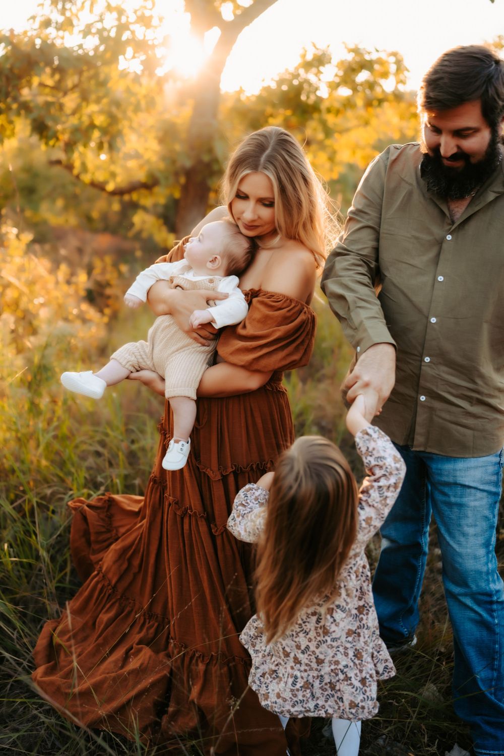 A family shares a playful moment together in a field during golden hour.