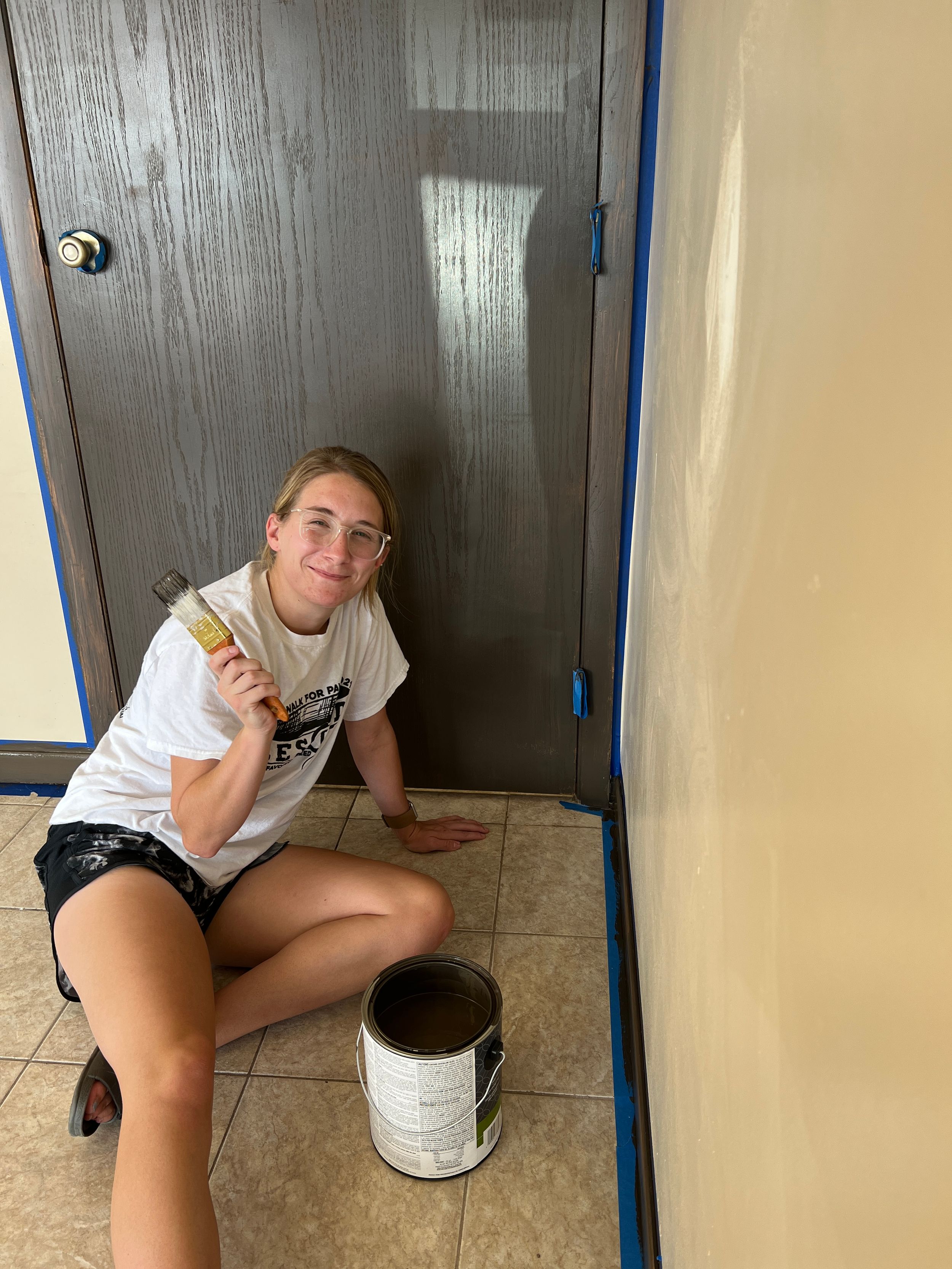 Person painting baseboards and trim during a renovation project.