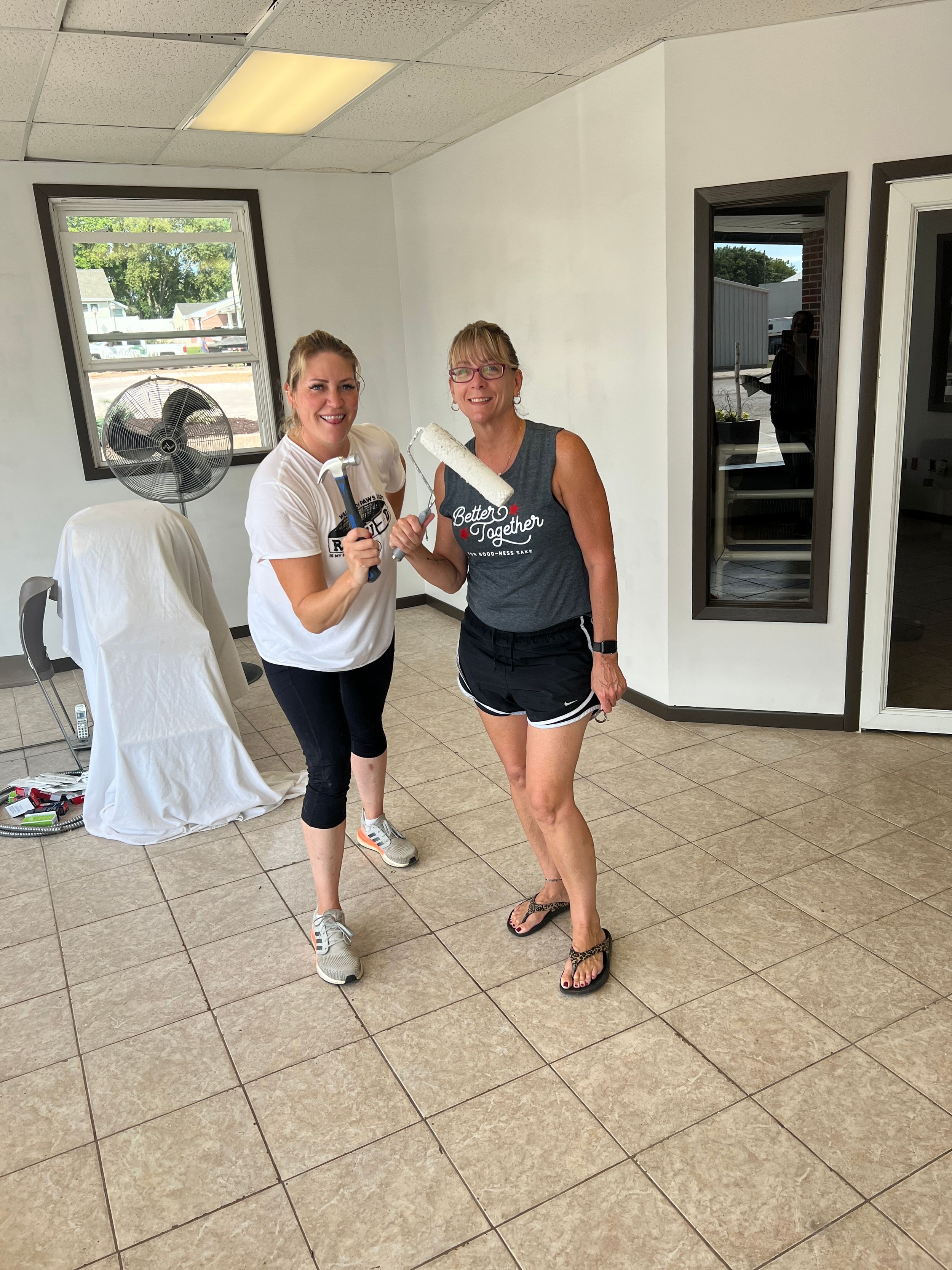 Team members cleaning and preparing floor tiles during renovation.