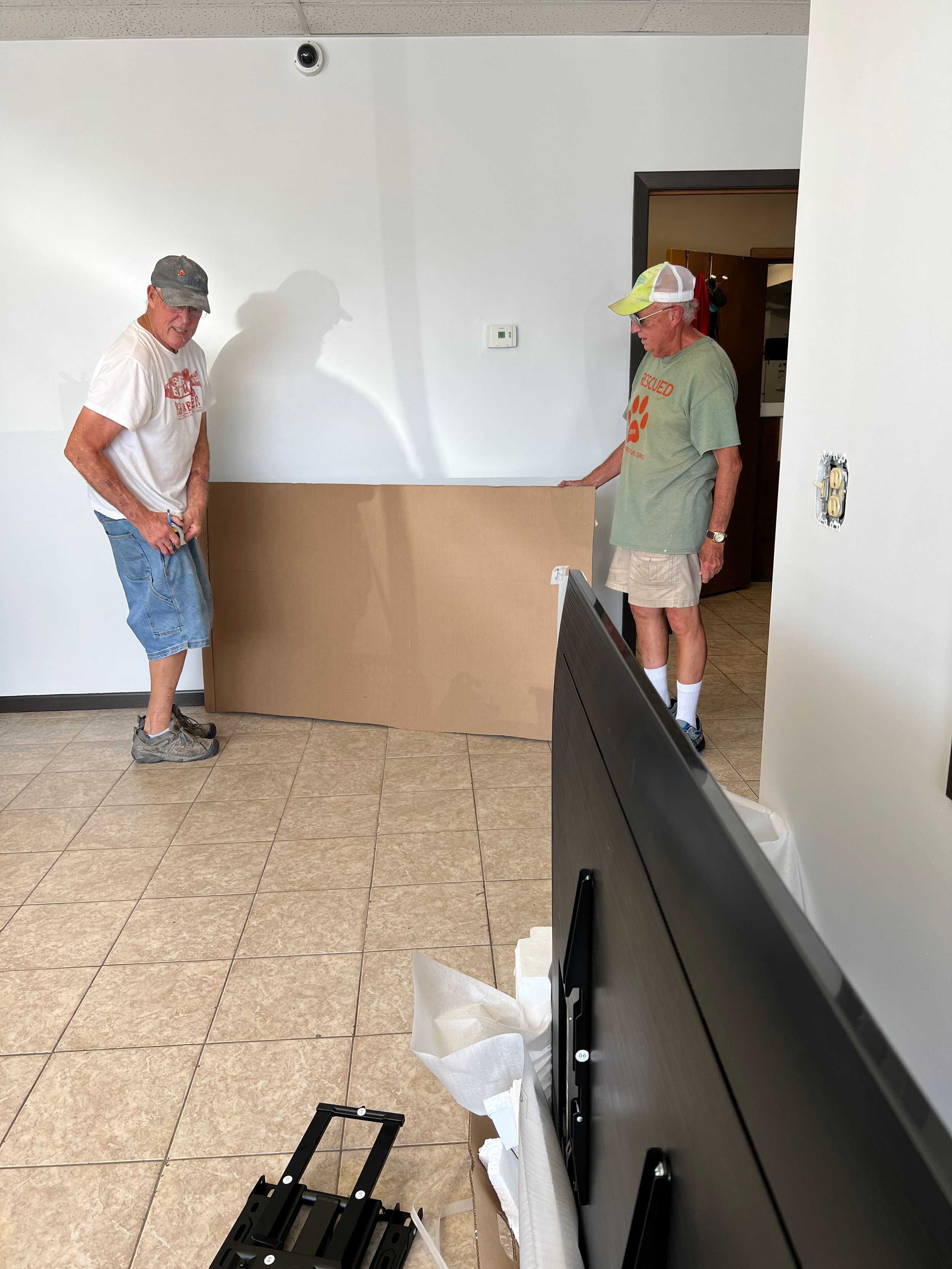 Workers installing black metal fixtures and equipment along interior walls.