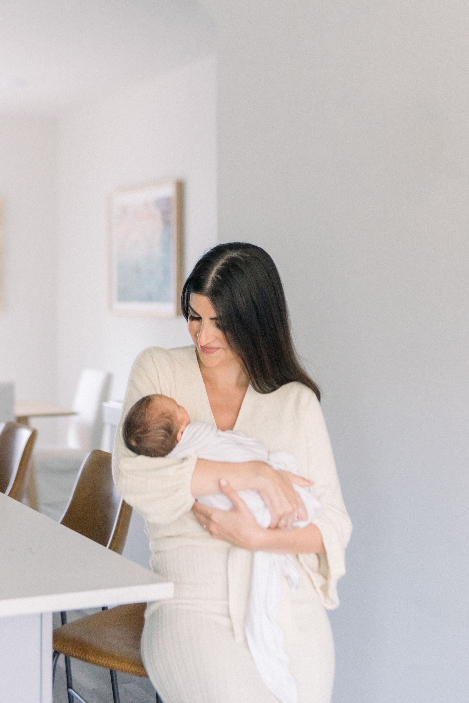 A peaceful moment in a bright room as someone in white cradles a sleeping newborn.