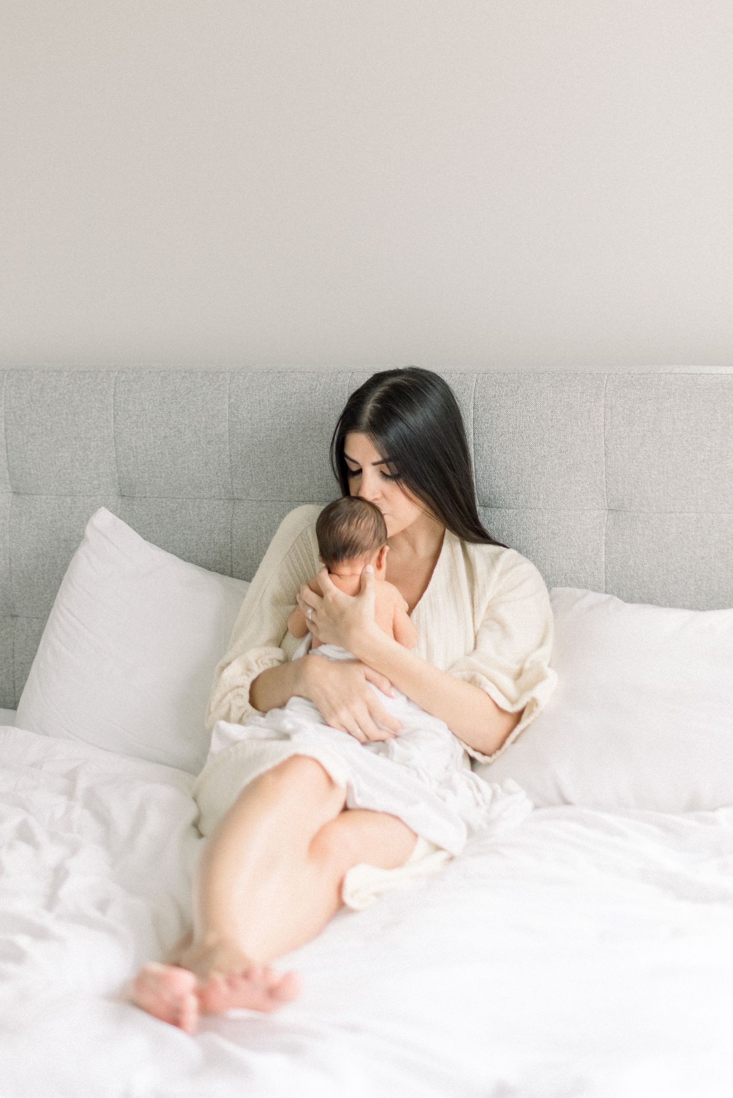 mom laying on bed kissing baby at Washington DC Newborn session