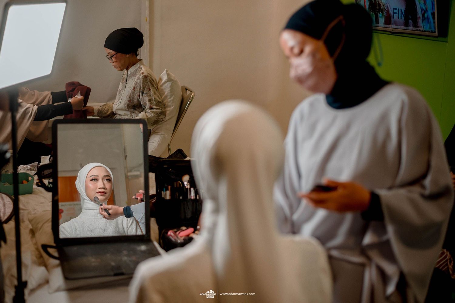 Behind the scenes of a hijab fashion photoshoot with makeup artists and stylists preparing models.