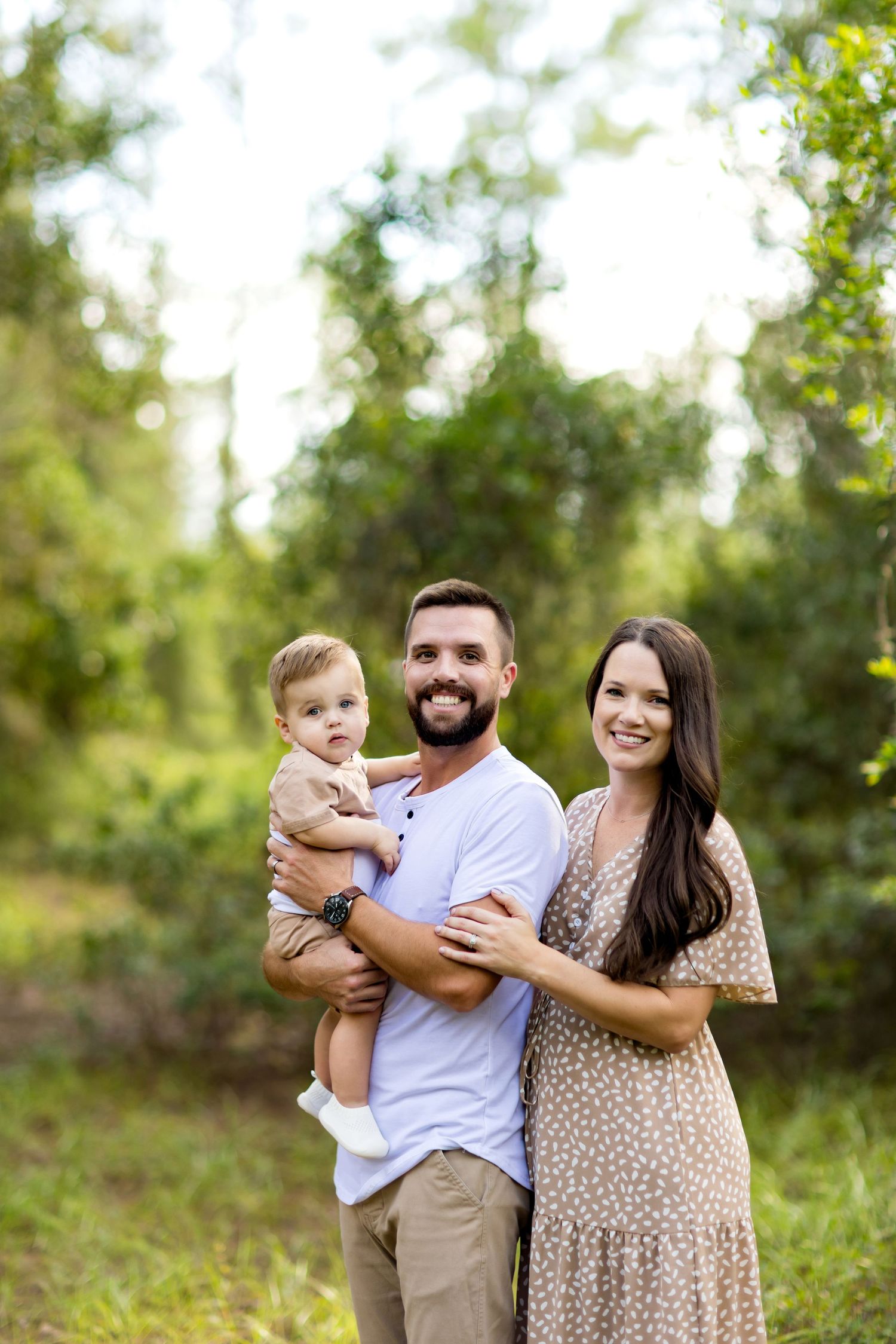 Happy family portrait in sunlit forest with matching casual outfits.