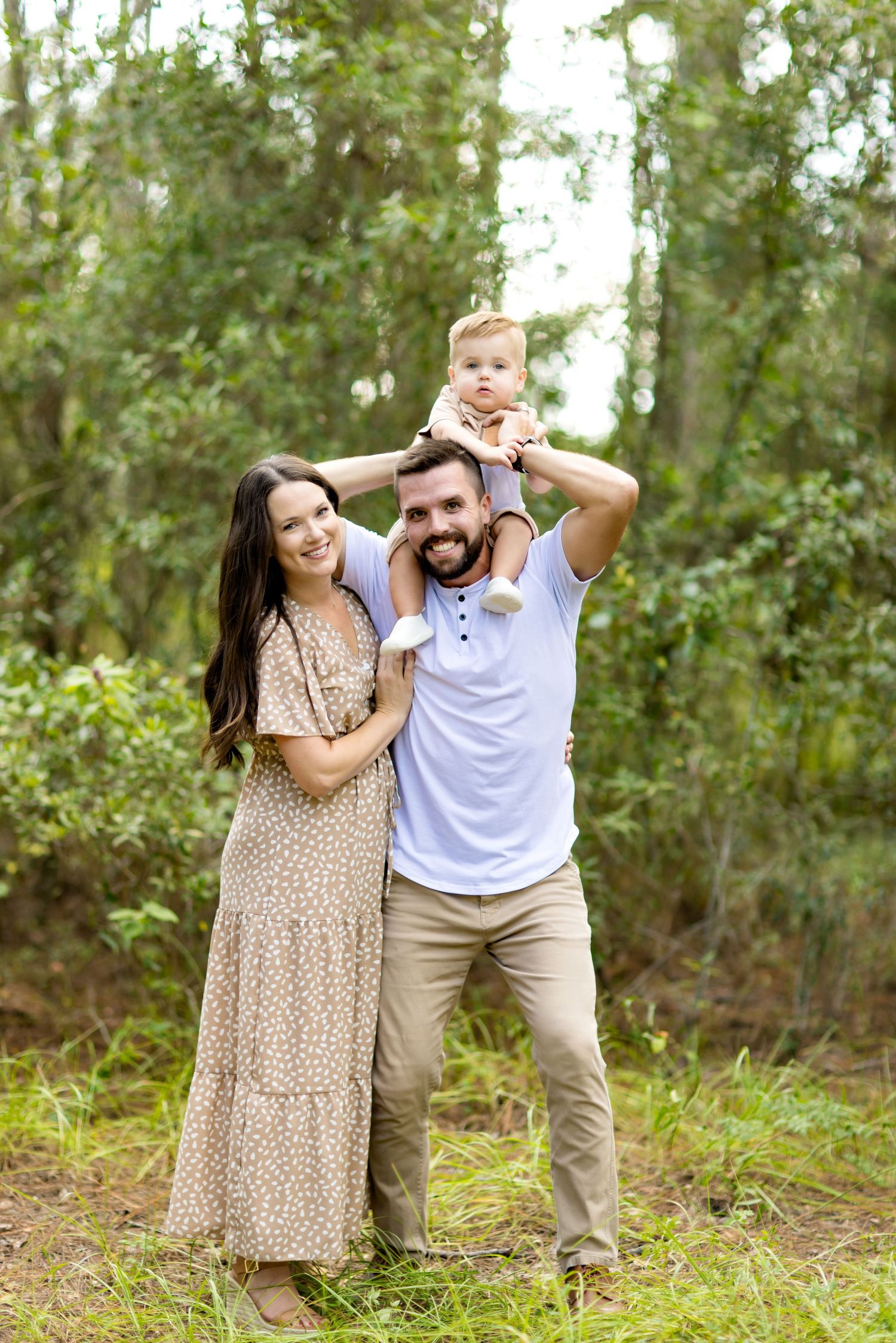 Playful family moment captured in a natural forest setting with sunlight filtering through trees.