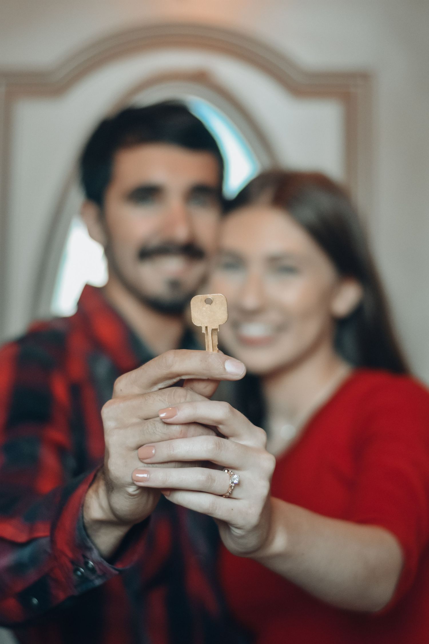 Couple holding up new house key together, celebrating home ownership.
