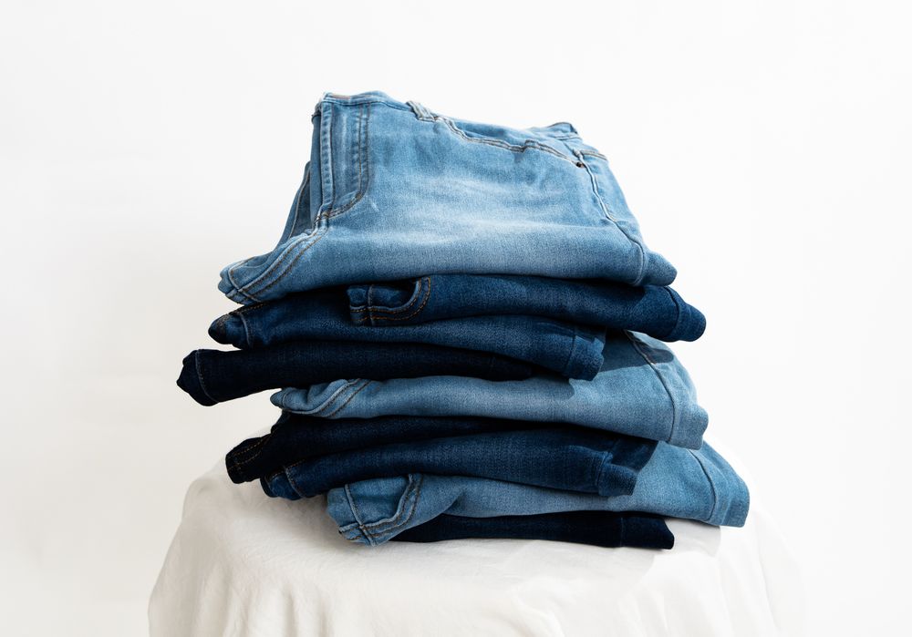 stack of 8 blue jeans in different washes, dark, medium and light