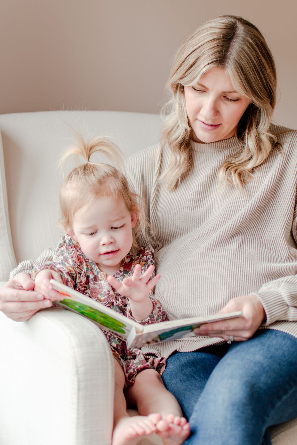 A mom and daughter share a bedtime story in the glider beside the window.