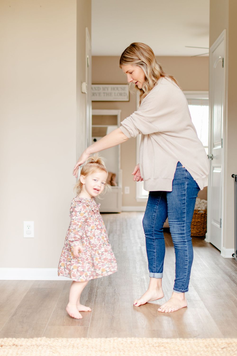 A little girl twirls in the hallway with her mother.