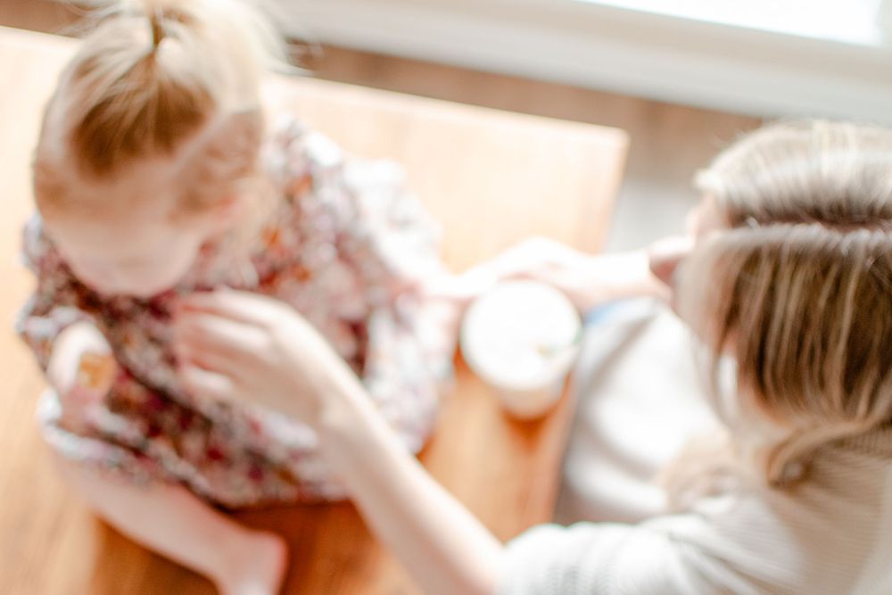 A mom and daughter share a special treat on top of the dining room table.
