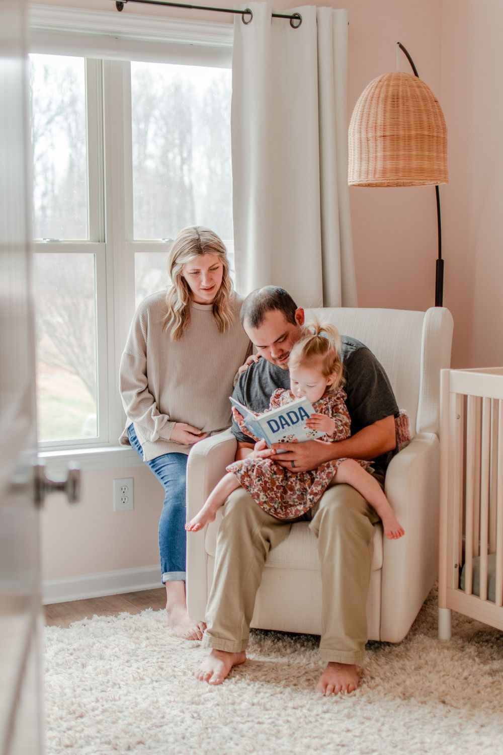 A family of three read stories together in the nursery.