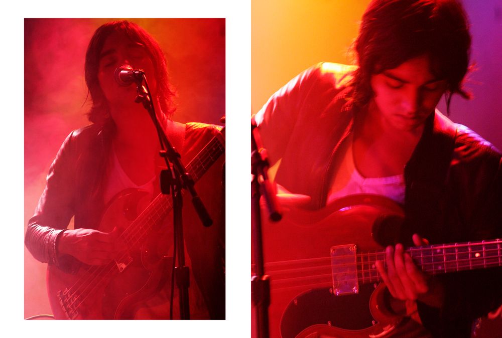 Musicians performing on stage with guitars under vibrant red and orange lighting effects.