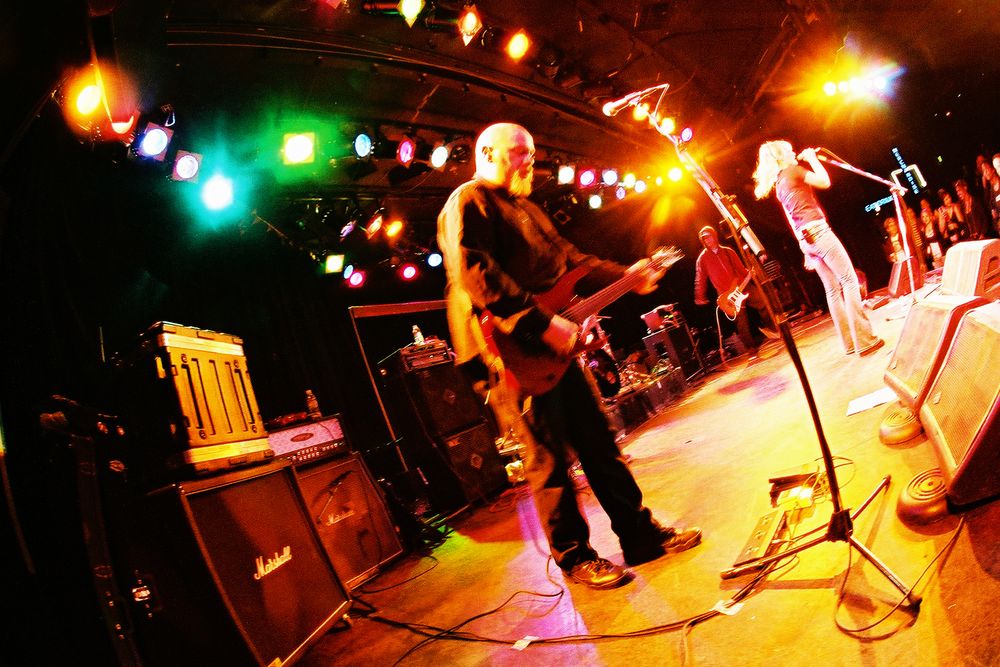 Musicians perform under colorful stage lights during an energetic concert.