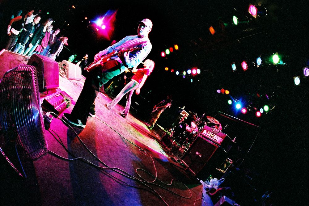 Wide-angle concert shot showing performers on stage with colorful lighting effects.