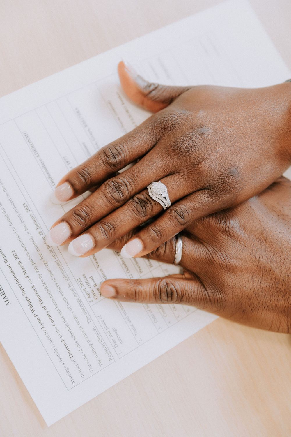 A hand wearing an engagement ring rests on legal marriage documents.