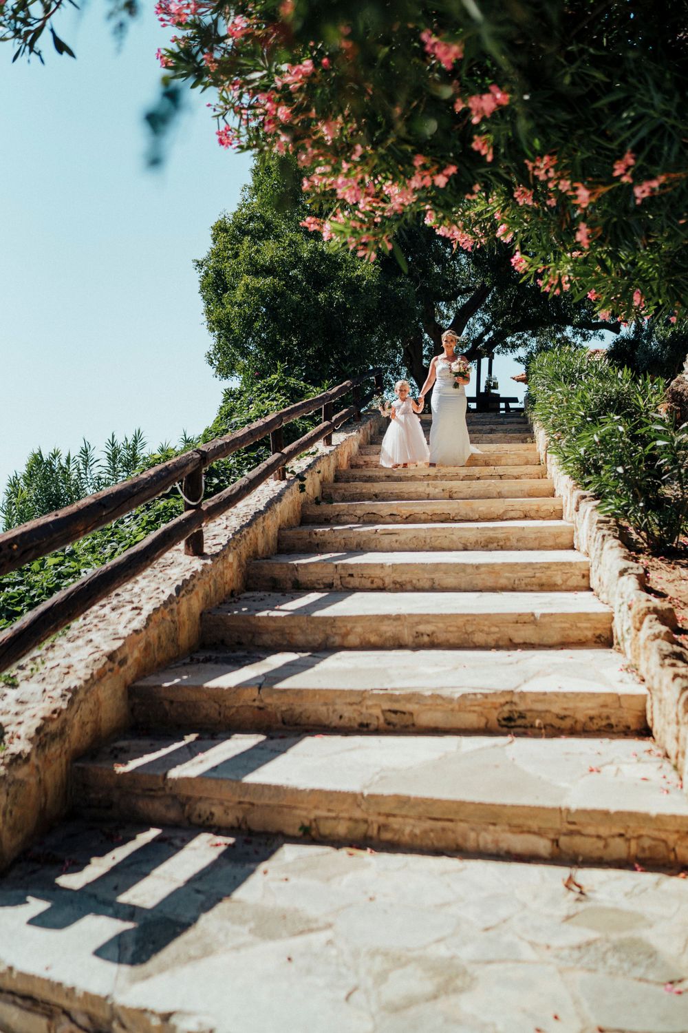 Stone staircase adorned with pink flowers and railings at a Mediterranean wedding venue.