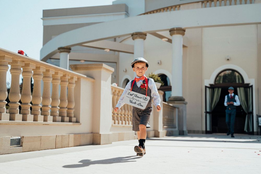A child in vintage newsboy attire runs through an elegant portico with white columns.