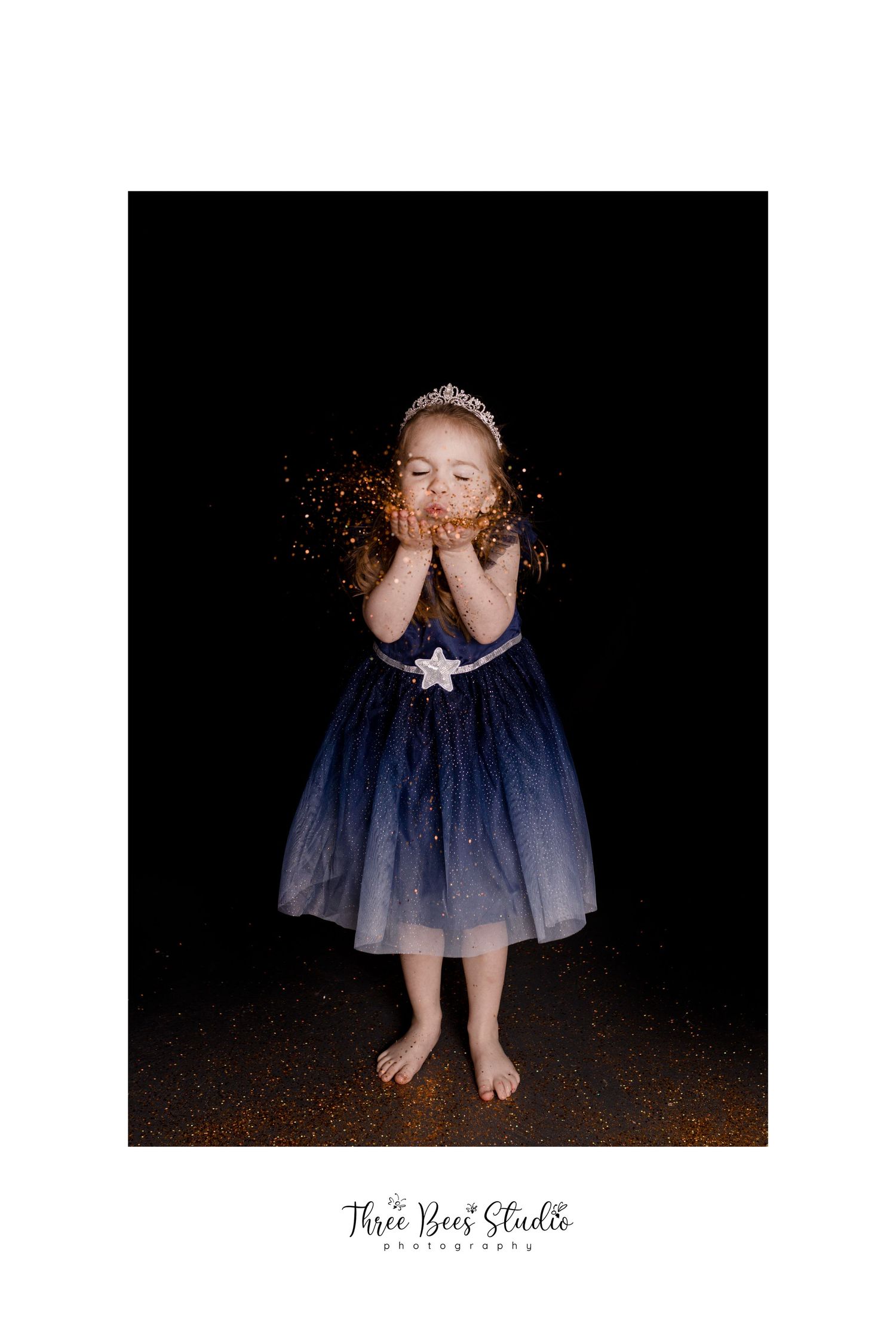 A magical portrait with gold glitter and a blue ombre dress against black background.