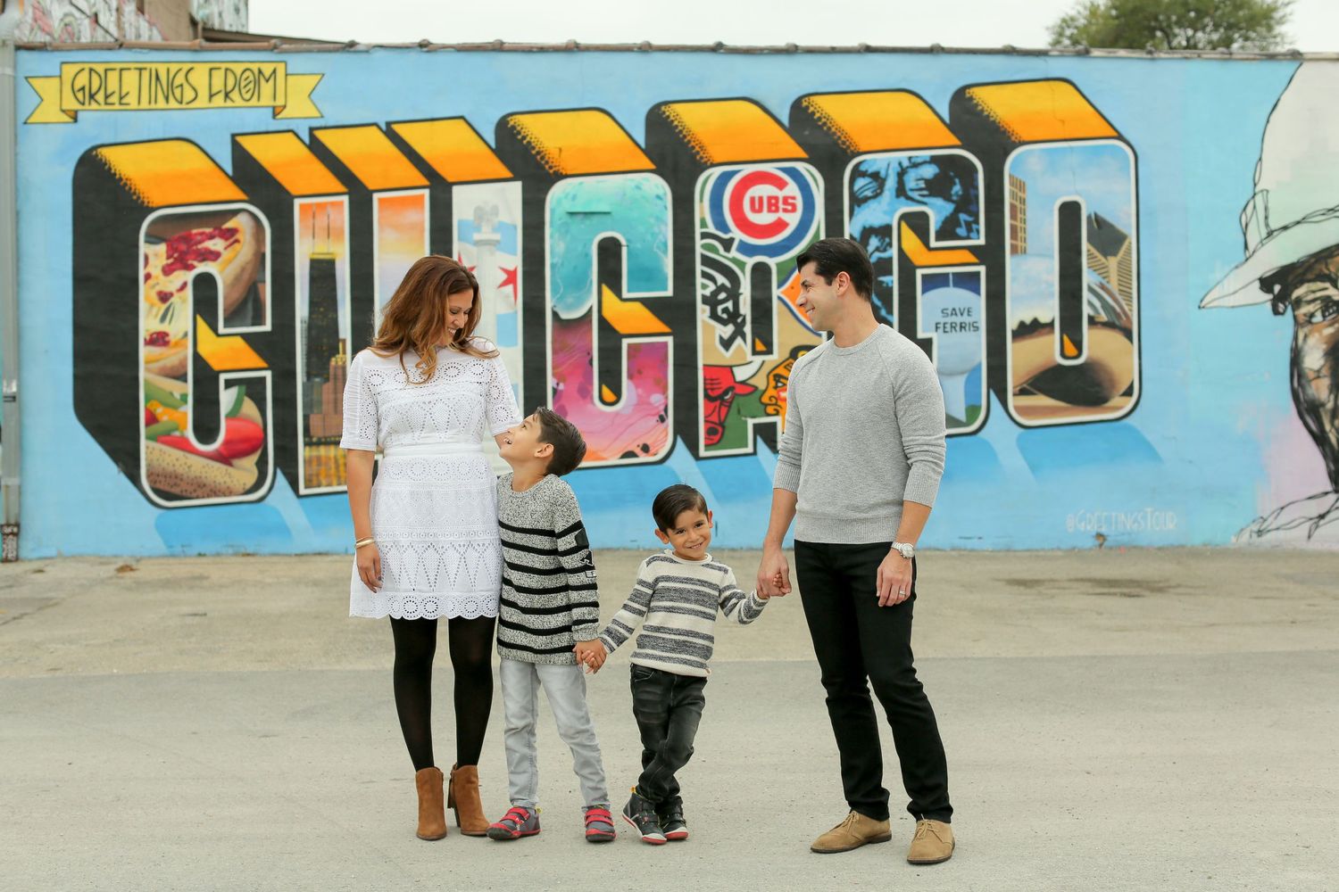 A family enjoying time together in front of a vibrant blue wall with colorful street art.