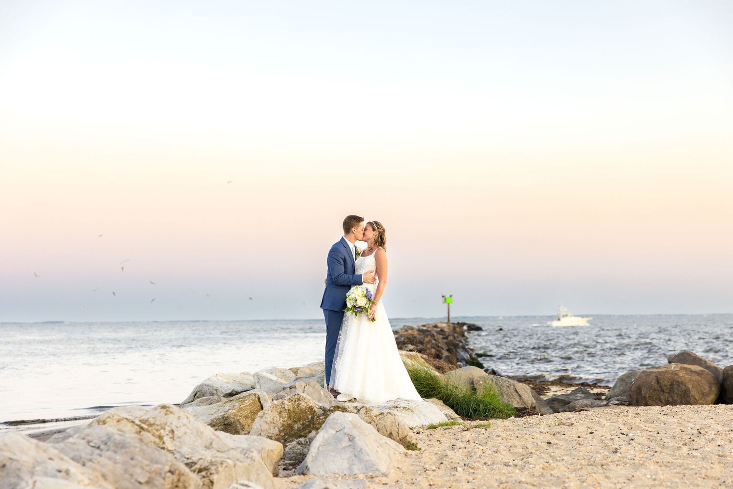 Romantic sunset wedding portrait among coastal rocks with ocean views.