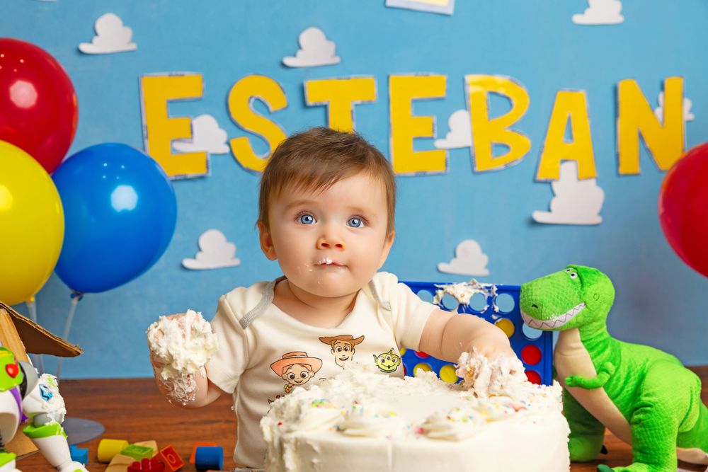 Birthday celebration scene with cake, colorful balloons and toys on wooden table.