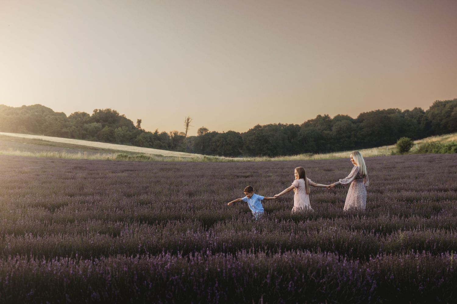 Silhouettes of people holding hands and running through a lavender field at sunset.