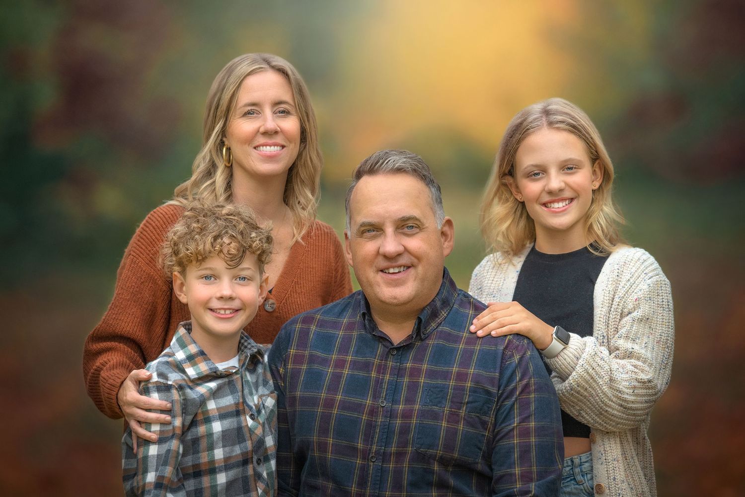 A warm autumn family portrait with a rustic outdoor background showcasing fall colors and a warm golden bokeh background.