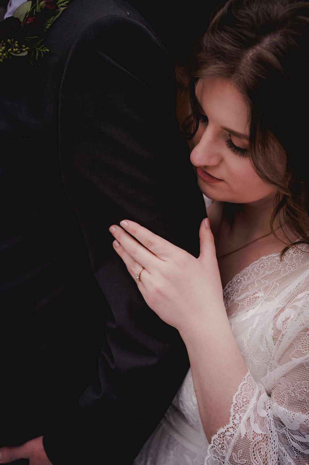 Artistic portrait in dark setting with person wearing delicate white lace dress.