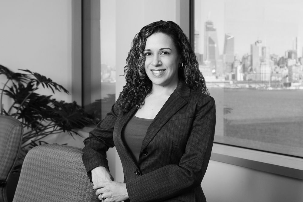 Professional portrait in business attire with city skyline in background.