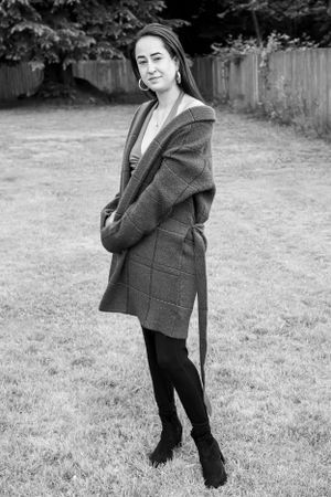 Black and white portrait of person in winter coat posing outdoors.