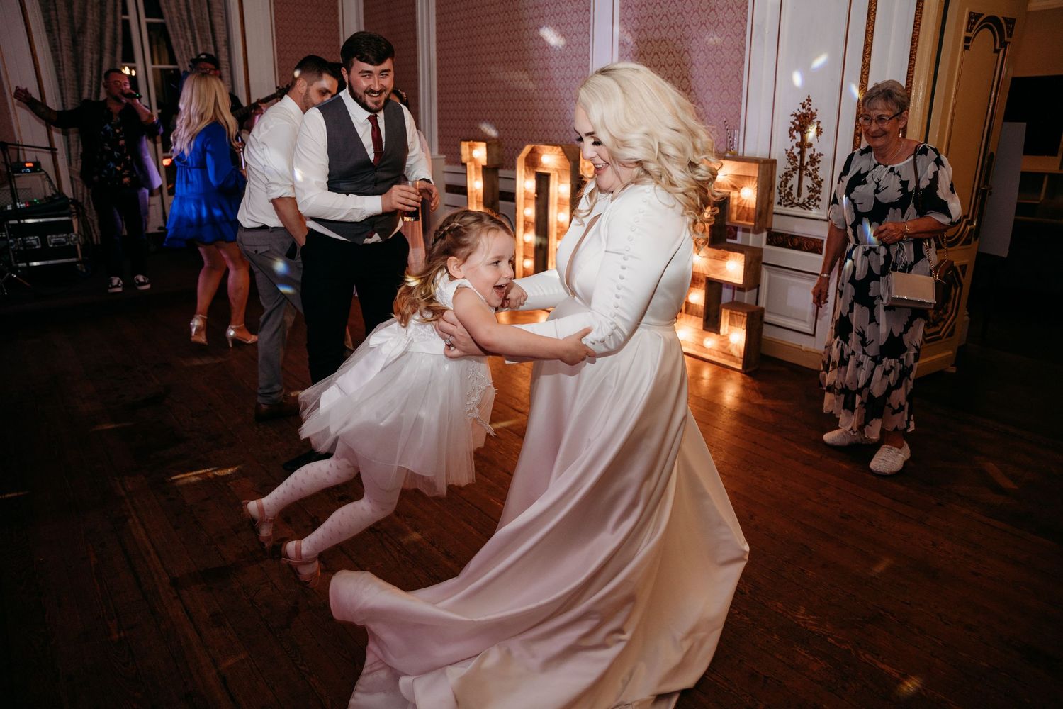 A flowing white dress twirls on the dance floor during a wedding celebration.