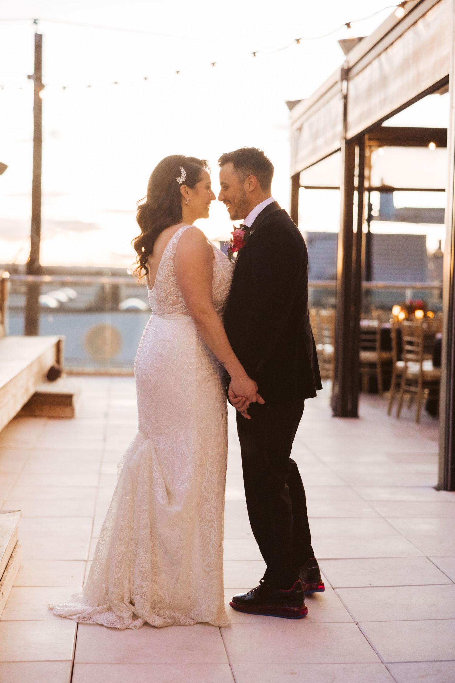 Romantic sunset moment between newlyweds on a rooftop terrace with string lights.