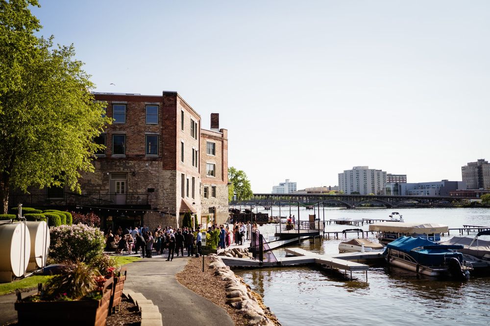 Historic waterfront building with boats docked along scenic riverbank.