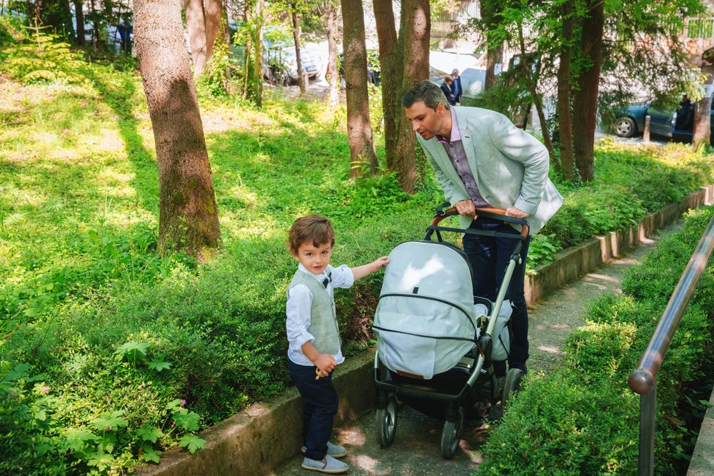 Walking through a park pathway with a stroller on a sunny day.