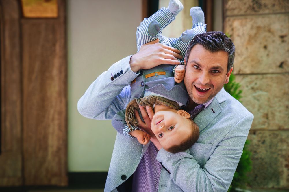 Candid playful moment captured outside historic building with stone architectural details.