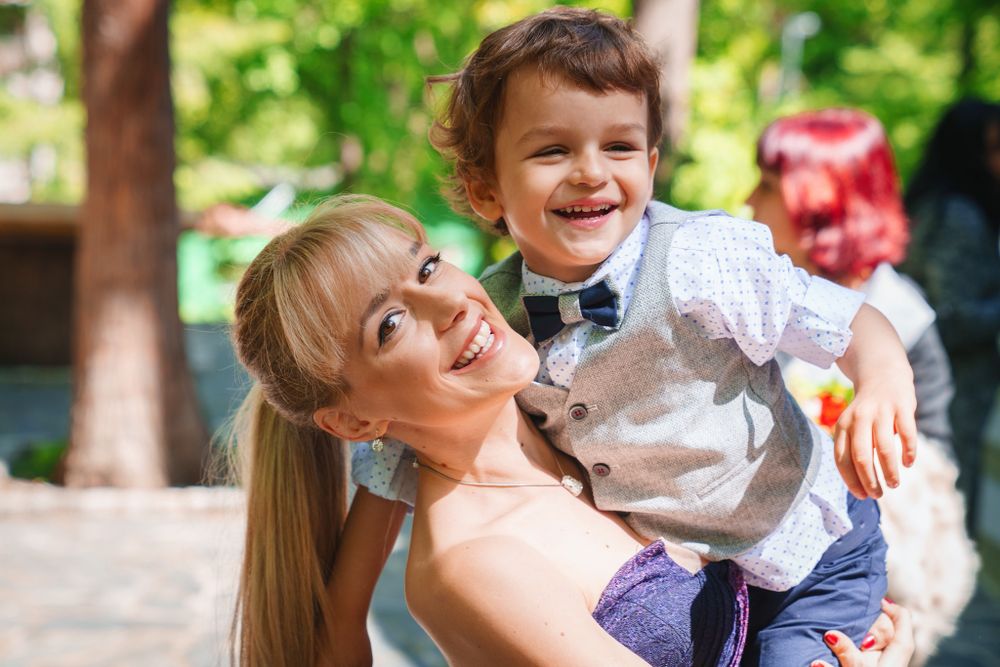Joyful outdoor portrait captured in a sunny park setting with trees in background.